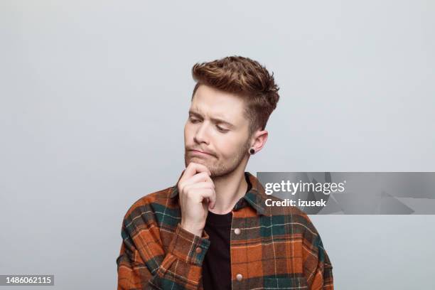 young man thinking with hand on chin - hand on chin stock pictures, royalty-free photos & images