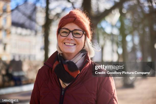 senior woman smiling while walking outside on a sunny winter day - mature woman winter stock pictures, royalty-free photos & images