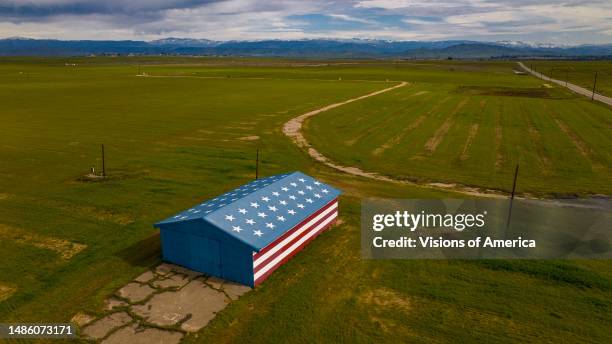 Aerial view of Red White and Blue Patriotic barn and green hills in fields outside of Fresno.