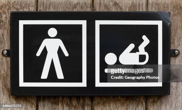 Male toilet sign with baby nappy diaper changing facility, UK.