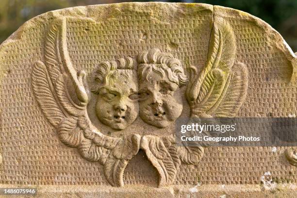 Faces of two cherubs or angels carved on gravestone, Shottisham, Suffolk, England, UK.