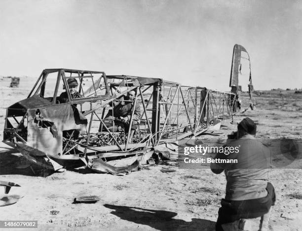 Soldiers pose for a photograph in the burnt-out wreck of a German fighter plane at an unidentified location in Tunisia, March 2nd 1943. The location...