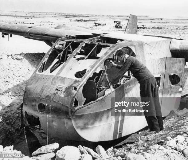 Man inspects the wreck of a German glider plane captured by British forces in the Western Desert of Libya, circa 1942.