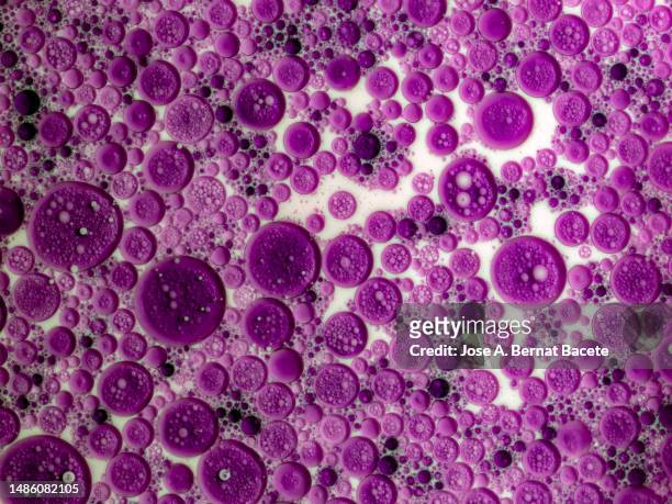 close-up of bubbles of pink liquid floating on white liquid. - stem cell background stock pictures, royalty-free photos & images
