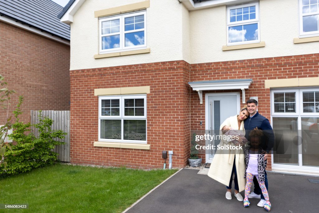 Happy Family in Front of Their Home