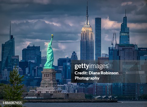 View of the Statue of Liberty and the Empire State Building with the late afternoon light shining down.