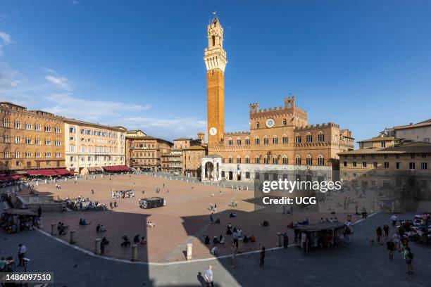 Siena, Siena Province, Tuscany, Italy. The Palazzo Pubblico with the Torre de Mangia seen across the Piazza del Campo. The historic center of Siena...