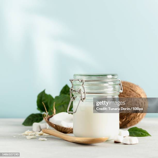 coconut oil in jar with fresh coconut and tropical leaf shadow,square composition,romania - kokosnussöl stock-fotos und bilder