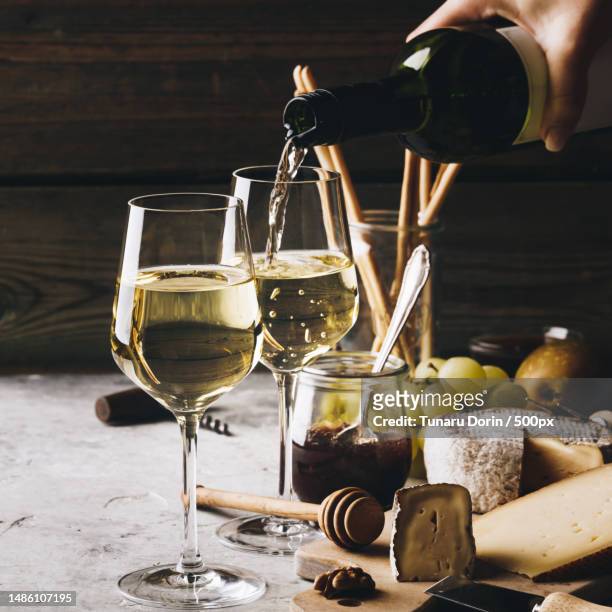 white wine pouring into glasses with charcuterie assortment,romania - wine bottle stock pictures, royalty-free photos & images