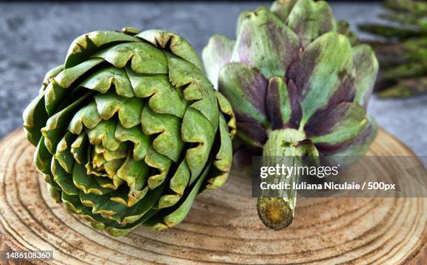 artichokes with greens on a wooden stand - artichoke stock pictures, royalty-free photos & images
