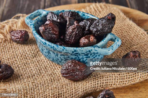 dried mission figs in glass bowl on burlap and wooden background - dörrpflaume stock-fotos und bilder