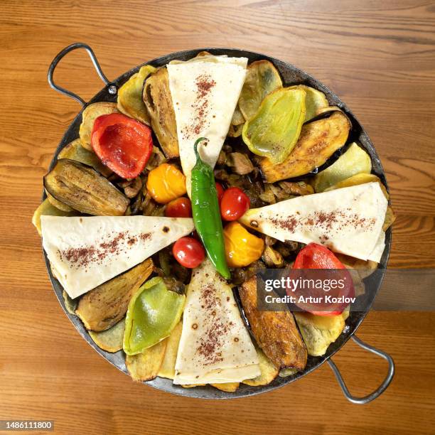 baked vegetables and pieces of pita bread in metal brazier. fried eggplant, potatoes, peppers, tomatoes in pan. vegetarian dish. view from above. wooden background. copy space - lavash stock pictures, royalty-free photos & images