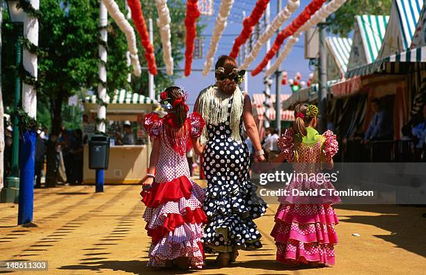 rear view of lady and girls wearing colourful flamenco dresses at feria de abril (april fair). - seville celebrates the feria de abril stock pictures, royalty-free photos & images