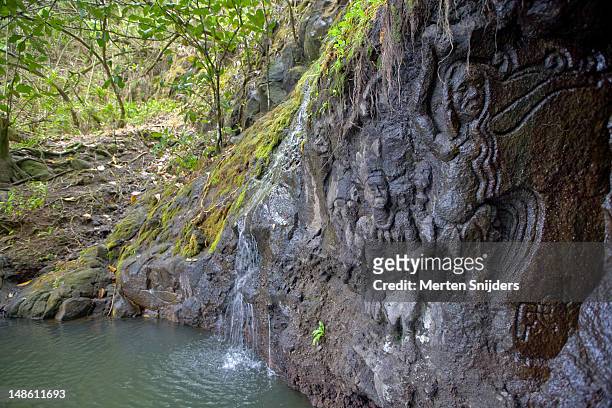 sculpture carved into rock at papeanaana waterfall. - tahiti waterfall stock pictures, royalty-free photos & images