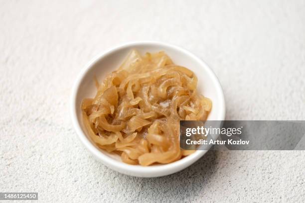 caramelized onions in white plate. onion fried in pan. component for cooking. roasting. white background. view from above. soft focus. copy space - cebolla fotografías e imágenes de stock