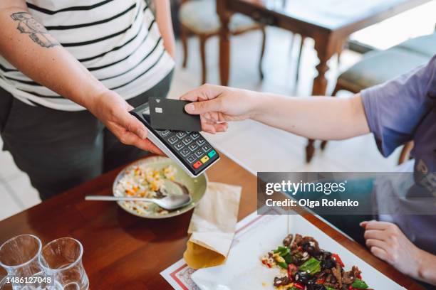 contactless payment in restaurant. wireless card reader scanning credit card from customer hand in cafe, high angle view - contactloze betaling stockfoto's en -beelden