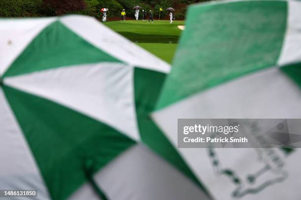 Hideki Matsuyama of Japan, Sungjae Im of South Korea and Cameron Smith of Australia look over their putts on the 12th green during the continuation...