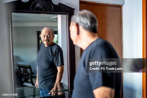 senior man looking in the mirror at home - low self esteem stock pictures, royalty-free photos & images