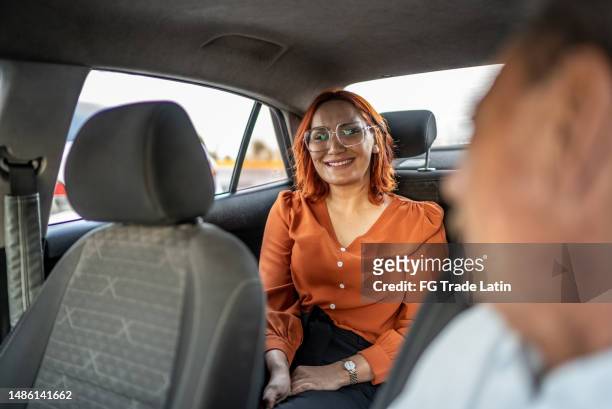mid adult woman talking to chofer during a taxi drive - car sharing stock pictures, royalty-free photos & images