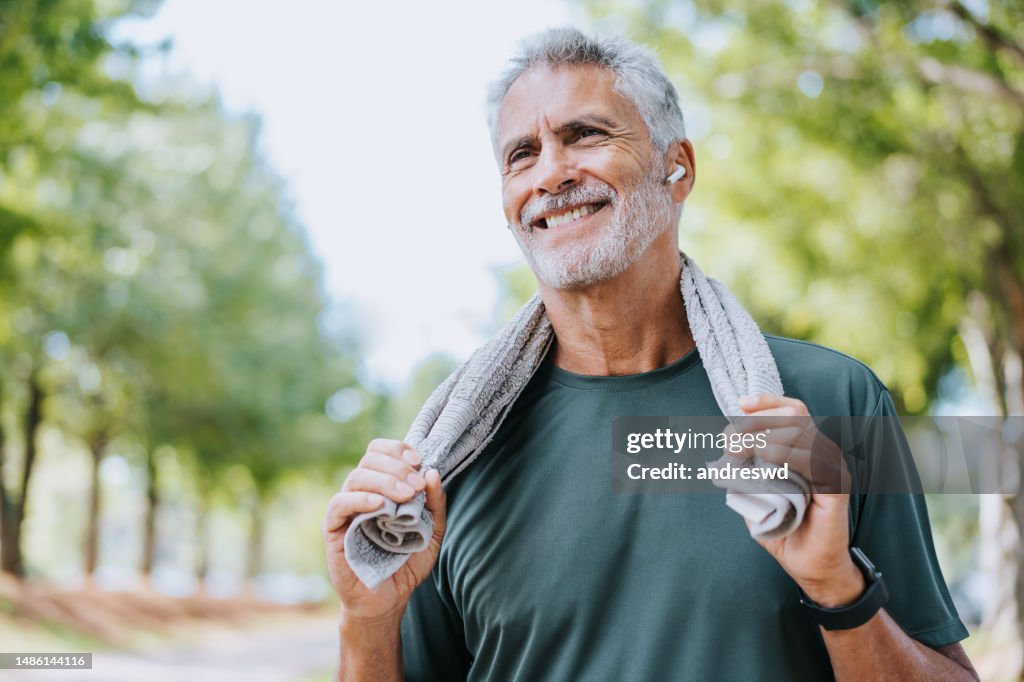 Corredor senior sosteniendo una toalla alrededor del cuello