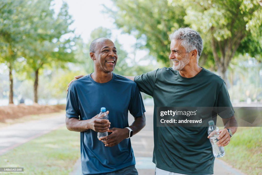 Amigos mayores caminando en el parque público