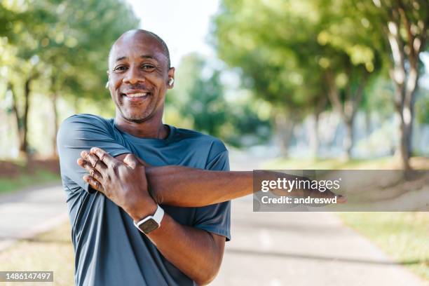 ritratto di un uomo maturo che fa stretching nel parco pubblico - fare lo stretching foto e immagini stock