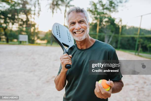 senior man playing beach tennis looking at camera - active seniors stock pictures, royalty-free photos & images