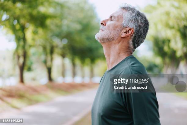 portrait of senior man breathing fresh air in nature - senior inhaling stock pictures, royalty-free photos & images