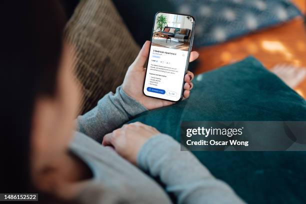 young woman looking for apartment to rent via online property platform with smartphone - inquadratura da sopra le spalle foto e immagini stock