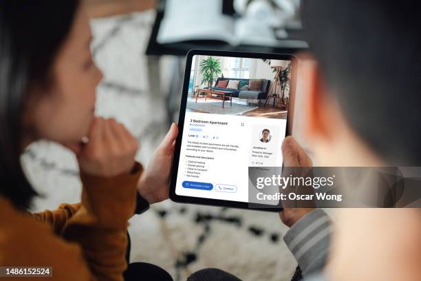 young asian couple looking for apartment to rent via online property platform with digital tablet - real estate listing stock pictures, royalty-free photos & images