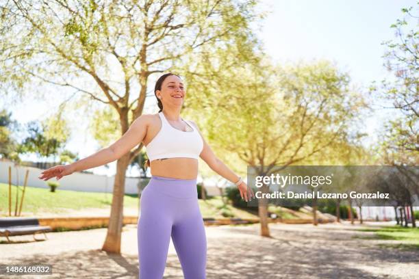 happy woman doing jumping jacks in a park - jumping jack stock pictures, royalty-free photos & images