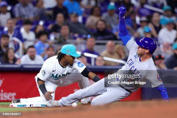 Cody Bellinger of the Chicago Cubs slides safe to third base against Jean Segura of the Miami Marlins during the seventh inning of the game at...