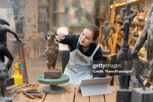 young woman creating pottery, using laptop - sculptor studio stock pictures, royalty-free photos & images