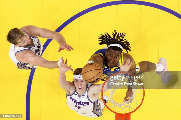 Kevon Looney of the Golden State Warriors goes for a rebound against Kevin Huerter and Domantas Sabonis of the Sacramento Kings during Game Six of...