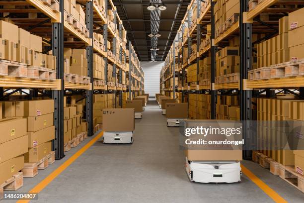 lagerinnenraum mit fahrerlosen transportfahrzeugen mit kartonagen - distribution warehouse stock-fotos und bilder
