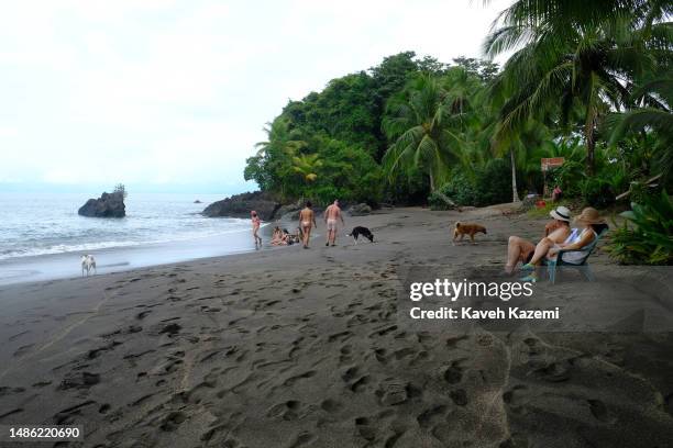 Tourists sitting by the shore on the Guachalito Beach on January 19, 2023 in Nuqui, Colombia.