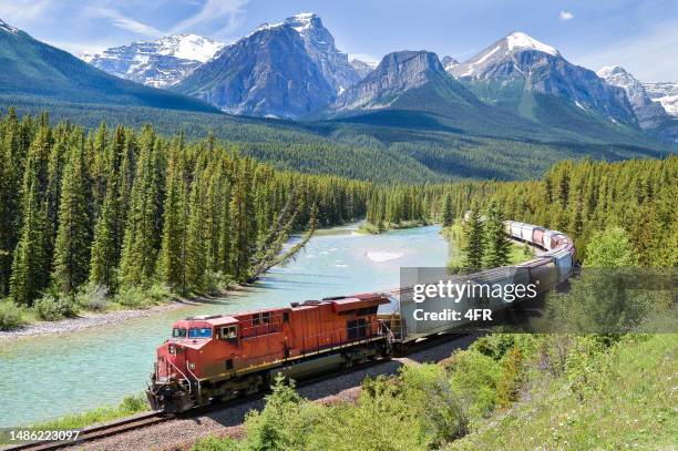 freight train moving along bow river in the canadian rockies, alberta, canada - canadese rocky mountains stockfoto's en -beelden