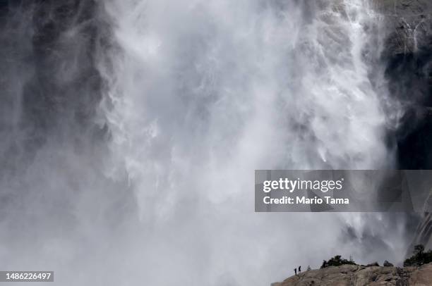 People are visible as torrents of water cascade down Upper Yosemite Fall in Yosemite Valley, as warming temperatures have increased snowpack runoff,...