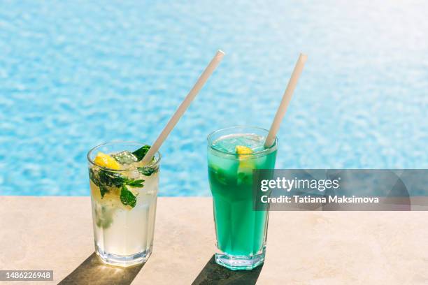 blue lagoon cocktail and mojito at the edge of the blue pool. - drinkwater kante stock-fotos und bilder