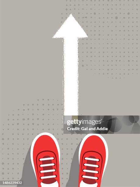 feet in sneakers stand in front of a drawn arrow - red shoe stock illustrations