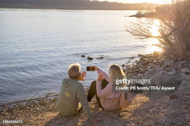 senior couple video call with mobile phone outdoors - lakeshore stock pictures, royalty-free photos & images
