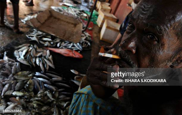 Sri Lankan fisherman smokes near his catch on the island's seaport town of Trincomalee on August 19, 2010. Fishing has hit hard times in the once...