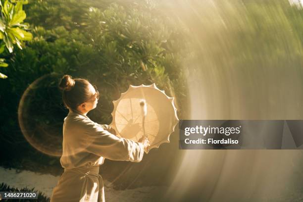 a woman practicing with cowhide shaman tambourine - rin gong 個照片及圖片檔