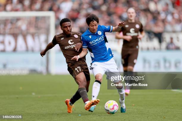 Masaya Okugawa of DSC Arminia Bielefeld is challenged by Oladapo Afolayan of FC St. Pauli during the Second Bundesliga match between FC St. Pauli and...