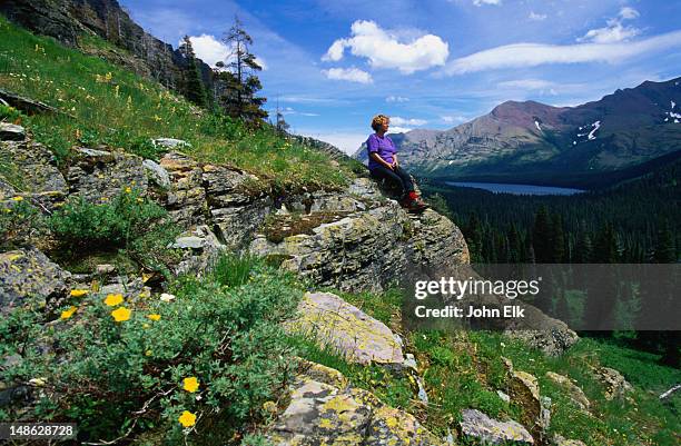 sitting on a rock at upper two medicine creek admiring the view of two medicine lake - glacier national park, montana - lago two medicine montana - fotografias e filmes do acervo