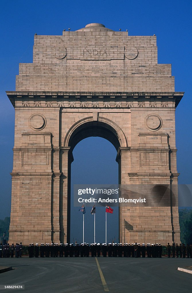 Soldiers standing at the base of India Gate, a 42 metre tall stone arch of triumph.