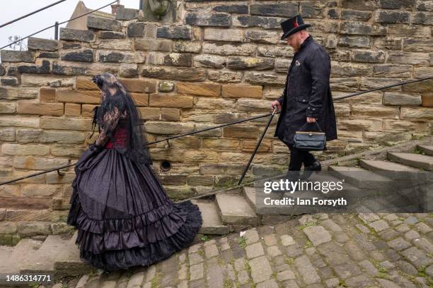 Couple in gothic clothing descend the steps from Whitby abbey during the Whitby Goth Weekend on April 29, 2023 in Whitby, England. The original...