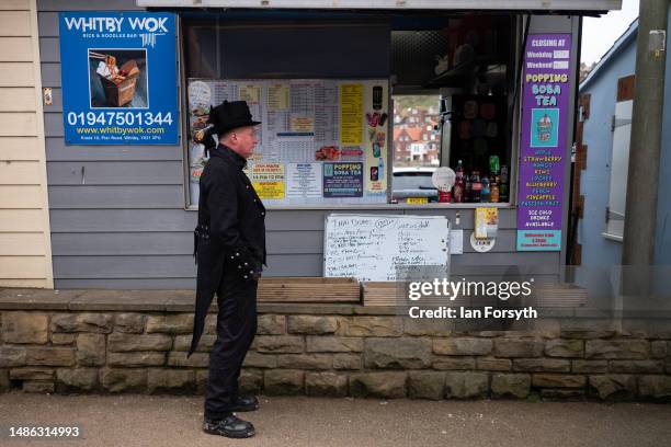 Man wearing gothic clothing stands at a food kiosk during the Whitby Goth Weekend on April 29, 2023 in Whitby, England. The original Whitby Goth...