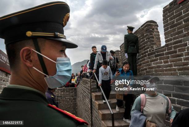 Members of the Peoples Armed Police stand guard as they do crowd control duty as visitors walk on the Great Wall while visiting the popular tourist...