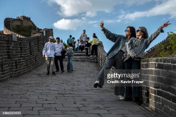 Two women take photos as they walk on the Great Wall while visiting the popular tourist site on the first day of the May Labour Day holiday on April...